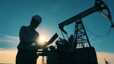 Bir petrol işçisi ve bir yağ tulumbası silueti. Petrol endüstrisi, ham petrol fiyatları kavramı.
