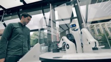 Çalışan robot garson ve bir müşteri. Gelecekçi robot kolu insanlara hizmet ediyor..