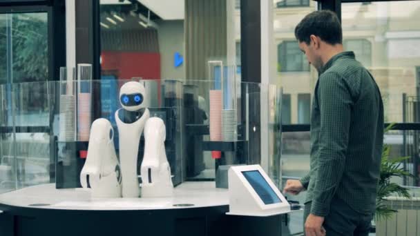 Man ordering coffee in a robotic coffee shop. Futuristic robotic arm works serving man. — Stock Video