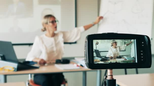 Een vrouw wordt gefilmd terwijl ze volwassen studenten online les geeft. — Stockvideo