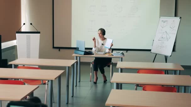 Tomma klassrum med en kvinnlig handledare som håller en online-klass — Stockvideo