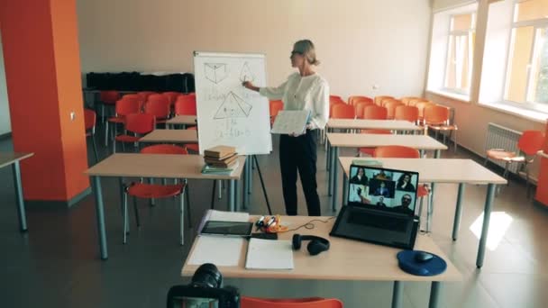 Une femme donne une leçon en ligne depuis une salle de classe vide. Enseignement à distance, enseignement en ligne, enseignement à distance, concept d'apprentissage en ligne. — Video