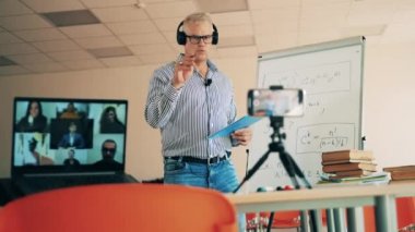 Erkek öğretmen online matematik sınıfını uzaktan yönetiyor.