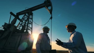 Petrol endüstrisi, ham petrol fiyatları konsepti. Petrolcüler yağ pompasının yanında el sıkışıyor.