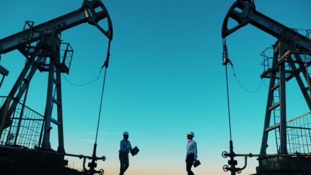 Trabajadores del petróleo estrechando manos entre los gatos de la bomba — Vídeos de Stock