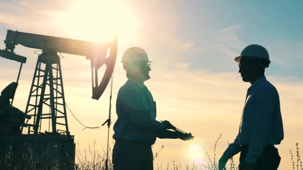 Due lavoratori petroliferi stringono la mano in un giacimento petrolifero — Video Stock