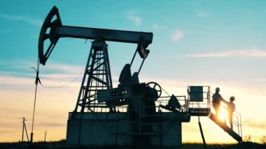 Mühendisler petrol pompalama ünitesinde dikilip konuşuyorlar.