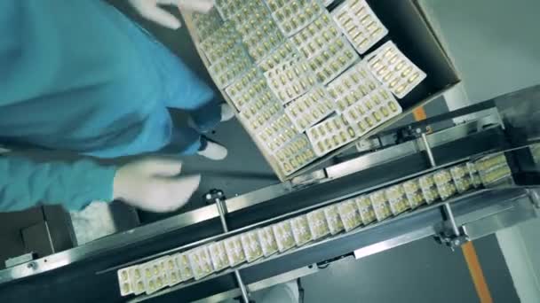 Fabrieksarbeider stopt blisterverpakkingen met capsules in een doos. Farmaceutisch bedrijf produceert antivirus. — Stockvideo