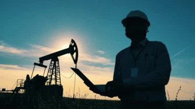 Petrol pompalama ünitesi ve erkek bir mühendis yakınlarda planlar yapıyor.