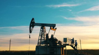 İki mühendis bir petrol pompalama ünitesini iş başında gözlemliyor.