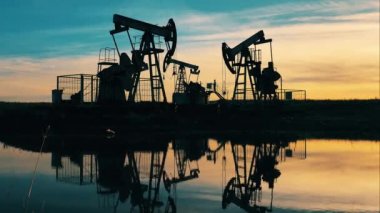 Petrol kuyusu, sondaj kulesi, petrol sahası, ham petrol fiyatı, petrol ve gaz, petrol varili, petrol endüstrisi konsepti. Gün batımında birden fazla pompalama ünitesi olan petrol çıkarma sahası.