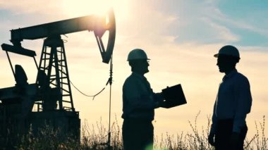 Petrol pompalama inşaat ve yanında el sıkışan iki mühendis