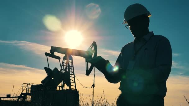 Olieput, ruwe olie, boorplatform, olieveld, prijs van ruwe olie, olie en gas, olievat, olie-industrie concept. Verlicht mannelijk ingenieur observeert een olieplaats. — Stockvideo