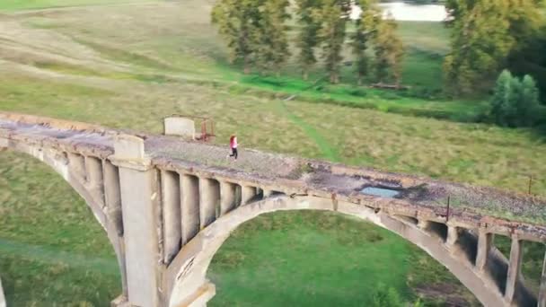 Old massive bridge with a sportswoman jogging along it — Stock Video