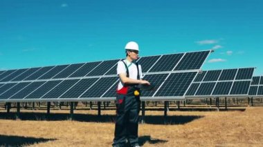 Erkek uzman bir güneş enerjisi üretim istasyonunu gözlemliyor