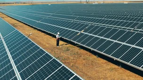 Estação de geração de energia solar está sendo inspecionada por um trabalhador — Vídeo de Stock