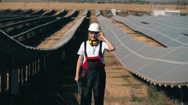 Ingeniero energético está de pie entre filas de paneles solares — Vídeos de Stock