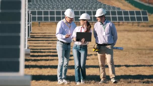 Arbeiter der Energetik gehen am Solarkraftwerk entlang — Stockvideo