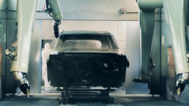 Robotlar otomatikleştirilmiş otomobil üretim hattında araba gövdesi boyuyor