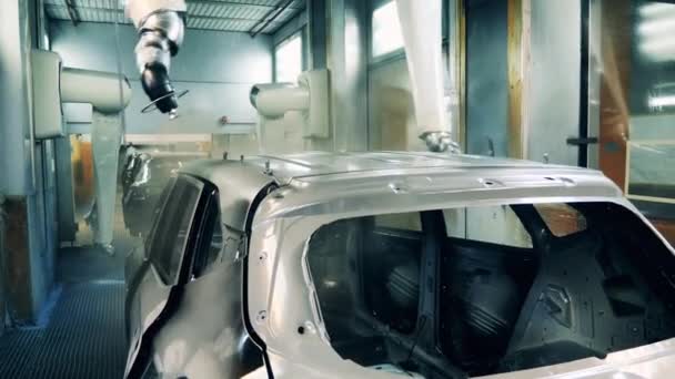 Robots spuiten een carrosserie op een assemblagelijn van een fabriek — Stockvideo