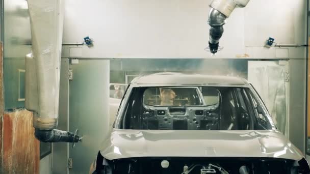 Robots peintres automobiles peignant une carrosserie dans une usine automobile. — Video