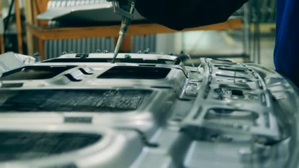 Travailleur d'usine appliquant de la colle sur une pièce de voiture. Intérieur de l'usine, équipement industriel. — Video