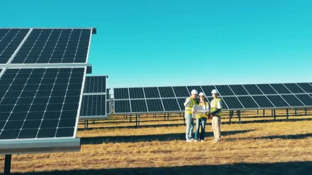 Grupo de engenheiros estão observando o campo de energia fotovoltaica em uma usina, conceito de energia solar. — Vídeo de Stock