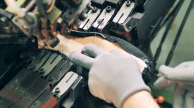 Sanayi işçisi mekanik olarak yeni bir botun tabanını yapıştırıyor.