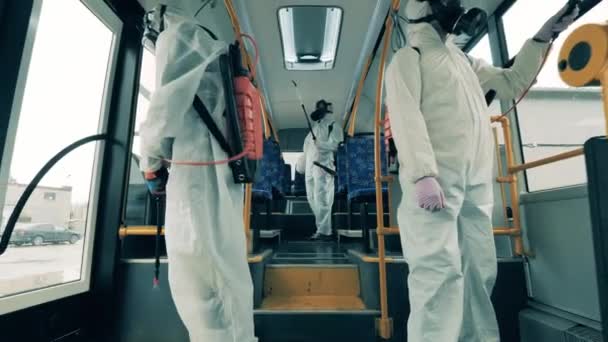 A közegészségügyi dolgozók takarítják a busz belsejét. Fertőtlenítés, vírusvédelmi fertőtlenítés, kovid-19 megelőzés. — Stock videók