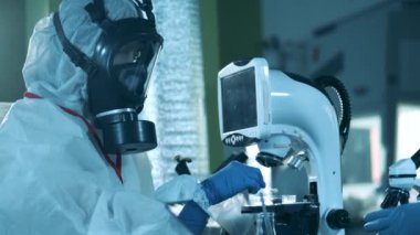 Laboratuvar uzmanı bilgisayarlı mikroskop üzerinde çalışıyor. COVID-19 'a antikor araştırması.