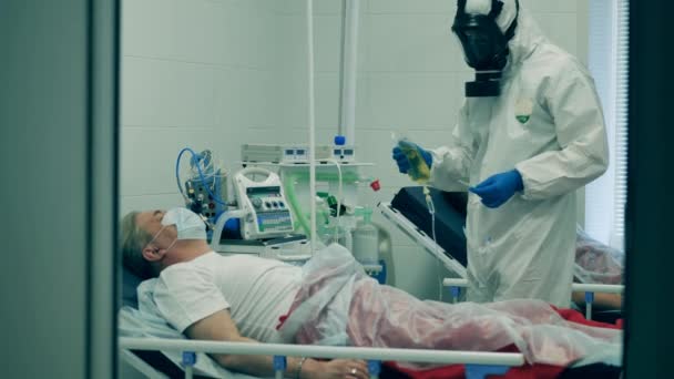 Pandemia koronawirusa, 2019-ncov, pojęcie koronawirusa. Pracownik medyczny w kombinezonie poda kroplówkę. pacjentowi — Wideo stockowe