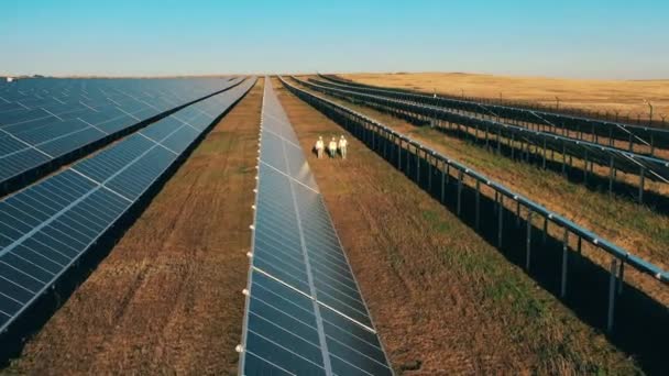 Centrale fotovoltaica con ispettori che la attraversano filmata dall'alto — Video Stock