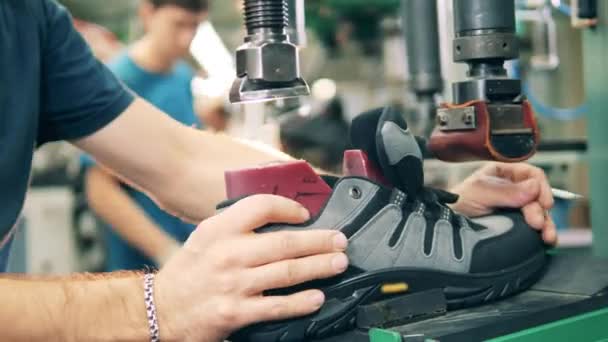 Un trabajador masculino está juntando una bota con su suela. Fábrica de producción de zapatos. — Vídeos de Stock