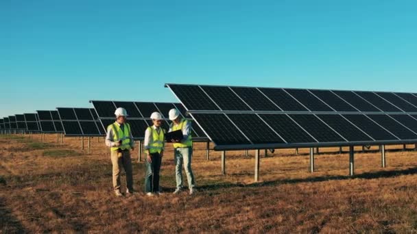 Os engenheiros estão a falar no meio de um campo de energia solar. Energia renovável, conceito de eletricidade solar. — Vídeo de Stock