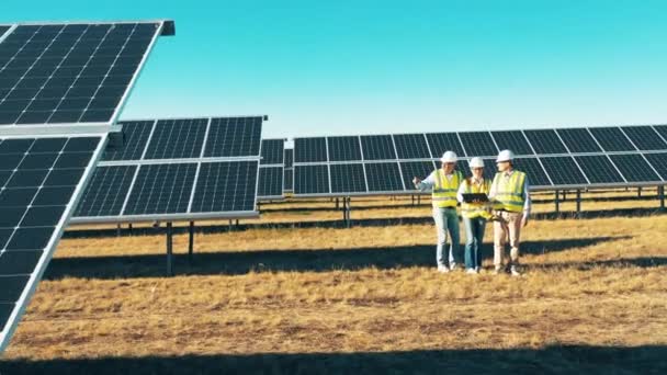 Campo de energia solar com uma equipe de inspetores tendo uma discussão. Conceito de energia solar. — Vídeo de Stock