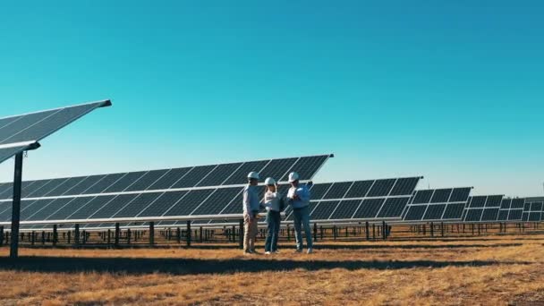 Sicherheitsinspektoren laufen über das Photovoltaikfeld. Ingenieure arbeiten im Solarkraftwerk — Stockvideo