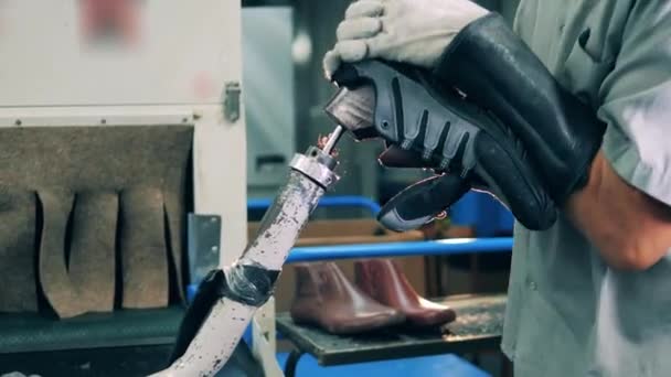 Ayakkabı fabrikası işçisi ayakkabısından bir şey çıkarıyor. Ayakkabıcılık endüstrisi konsepti. — Stok video