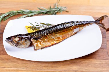 Biberiye ve limon dilim beyaz plaka üzerinde füme uskumru. Yakın çekim