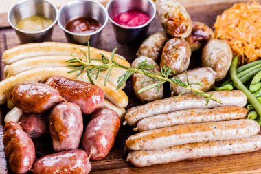 Oktoberfest yemek menüsü. Karışık ızgara sosis, lahana turşusu, ahşap kesme tahtası üzerinde taze fasulye. Yakın çekim