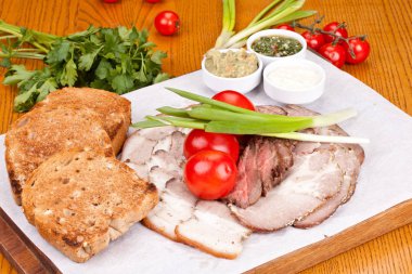 Kızarmış ekmek, domates, soğan ve beyaz plaka üzerinde soslar ile çeşitli soğuk et. Yakın çekim