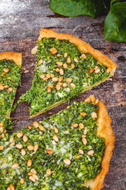 Ispanak, ricotta peyniri ve çam fıstığı ahşap rustik masa üzerinde tart. Yakın çekim