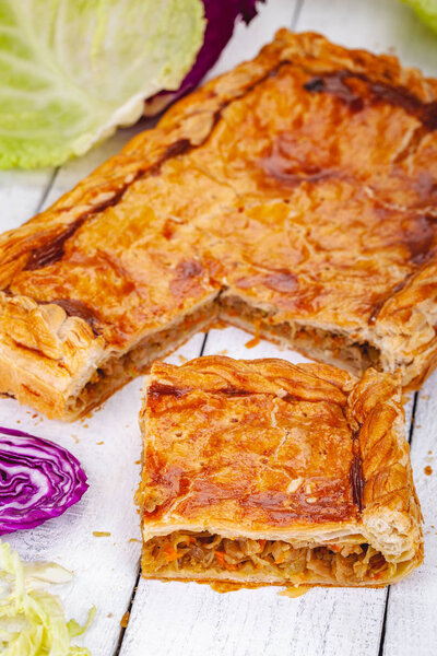 Homemade cabbage pie on wooden rustic background. Close up