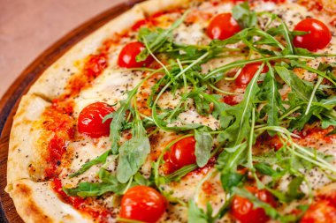 Domatesli İtalyan pizzası, mozarella peyniri ve ahşap kesim tahtasında roka. Kapat.