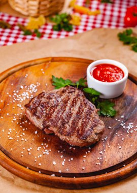 Ahşap kesme tahtası üzerinde domates soslu ızgara sığır eti biftek. Yakın çekim