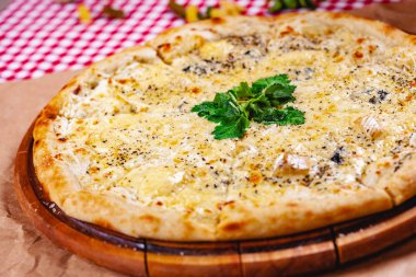 Tahta kesme tahtasının üzerinde İtalyan pizzası (quattro fromaggi). Kapat.
