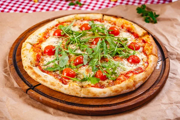 Domatesli İtalyan pizzası, mozarella peyniri ve ahşap kesim tahtasında roka. Kapat.