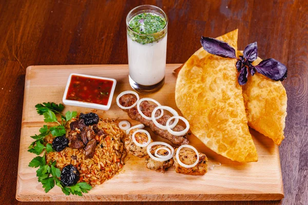 Ortadoğu mutfağı. Börek, kebap, pilav, tahta kesme tahtasında ayran. Üst Manzara. Kapat.