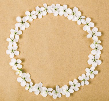 Yuvarlak kare çelenk kahverengi kağıt arka plan üzerinde beyaz bahar çiçekleri yapılmış. Üstten Görünüm. Düz yatıyordu.