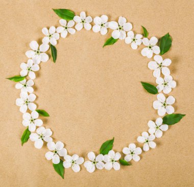 Yuvarlak kare çelenk beyaz bahar çiçekleri yapılmış ve yeşil kahverengi kağıt arka plan üzerinde bırakır. Üstten Görünüm. Düz yatıyordu.