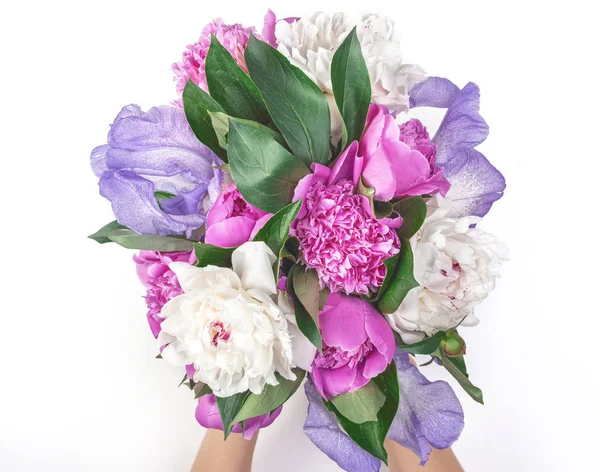 Buket pembe ve beyaz peonies ve irisler beyaz arka plan üzerinde izole kadın'ın elinde. Üstten görünüm. Düz yatıyordu.